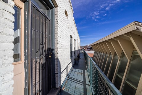 A balcony with a black railing and a view of a street below.