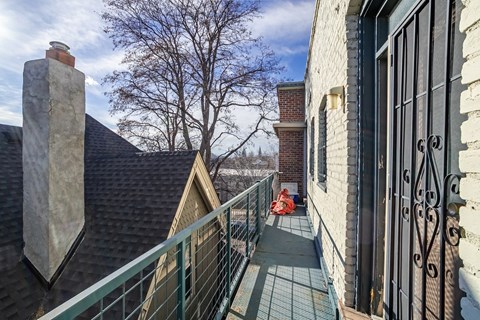 A balcony with a metal railing and a brick chimney.