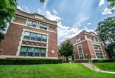 Two red brick buildings with green lawn in front.