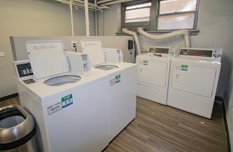 A series of white machines with labels on them are in a room with wood flooring.