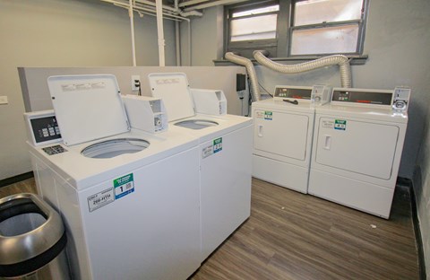 A series of white machines with labels on them are in a room with wood flooring.