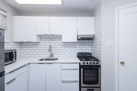 A kitchen with white cabinets and a black stove top oven.