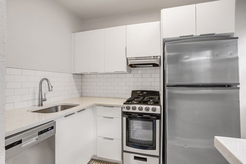 A modern kitchen with white cabinets and stainless steel appliances.