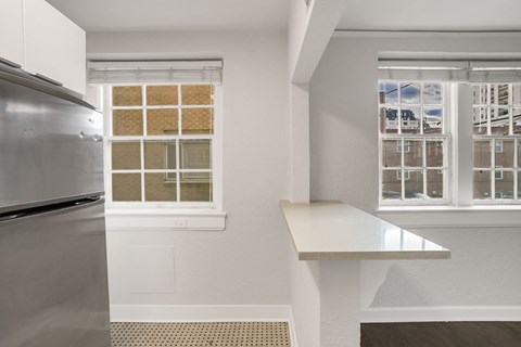 A kitchen with a refrigerator and a window with a view of buildings outside.