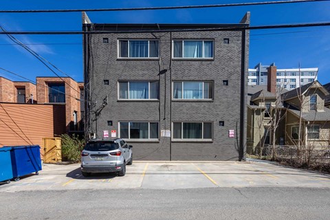 A grey building with a car parked in front.
