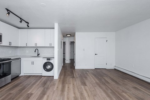 A kitchen with white cabinets and a wooden floor.