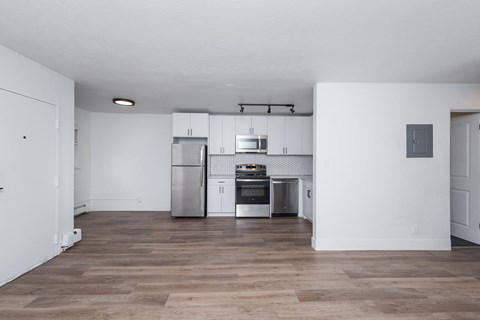 A kitchen with white cabinets and a wooden floor.