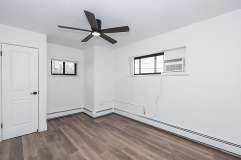 A room with a ceiling fan and a door.