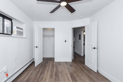 A room with a ceiling fan and wooden flooring.