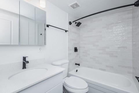 A white bathroom with a sink, toilet, and bathtub.