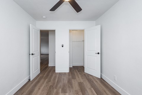 A room with a ceiling fan and wooden flooring.