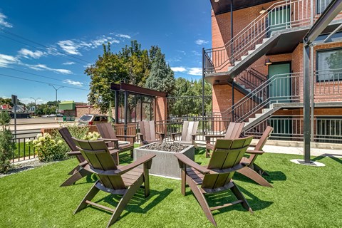 Two wooden chairs and a table are on a green lawn.