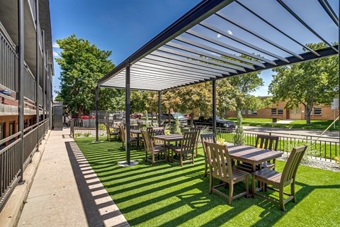 A patio with tables and chairs under a roof.