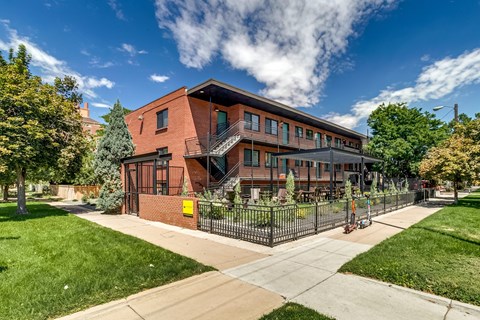 A red brick building with a black fence in front.