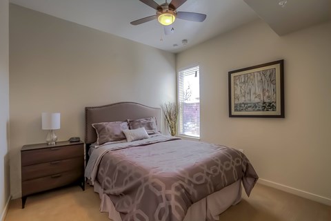 A bedroom with a bed, dresser, and a ceiling fan.