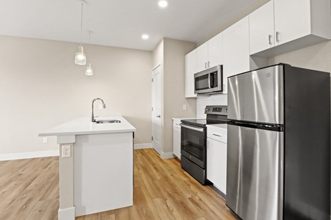 a white kitchen with stainless steel appliances and a white counter top