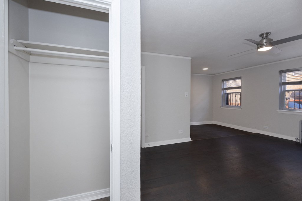 Empty room with a ceiling fan and two windows.
