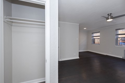 Empty room with a ceiling fan and two windows.