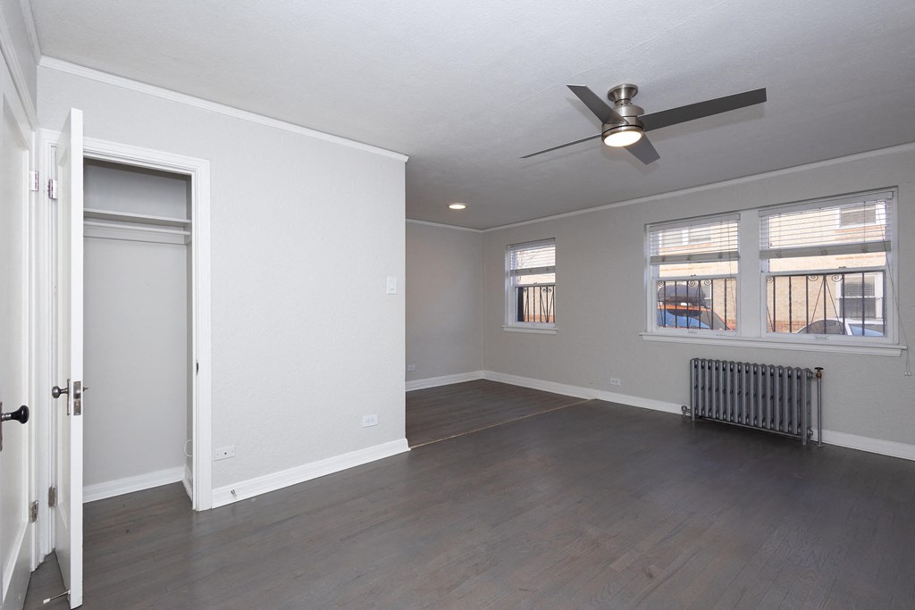 A room with a ceiling fan and a radiator on the floor.