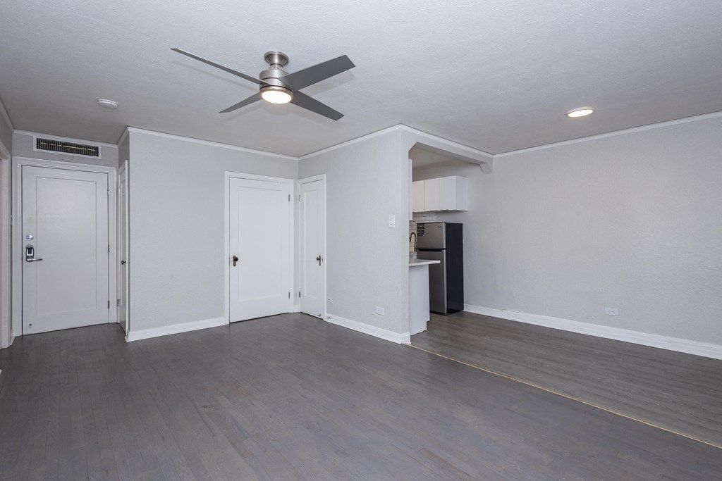 A room with a ceiling fan and wooden flooring.