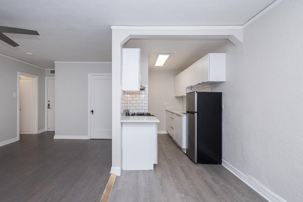 A kitchen with a black refrigerator and white cabinets.