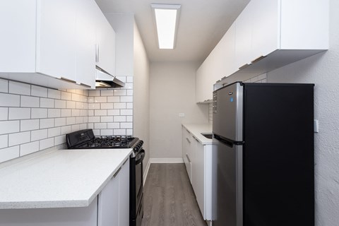 A kitchen with black appliances and white cabinets.