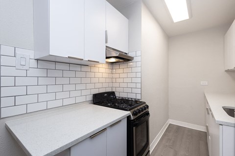 A kitchen with white cabinets and a black stove top oven.