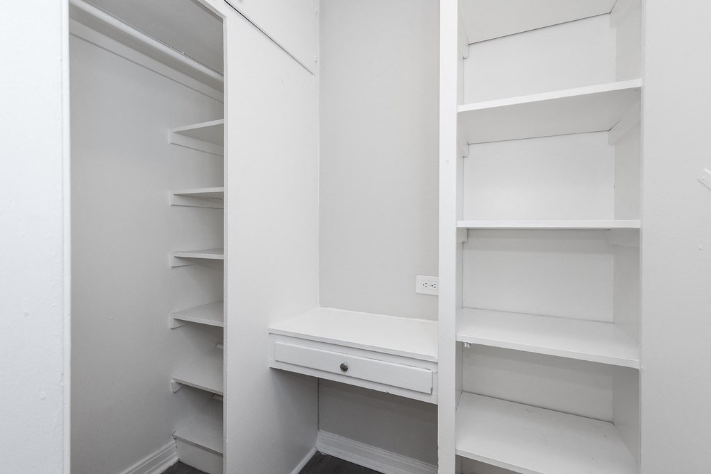 A white pantry with shelves and a drawer.