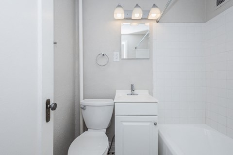 A white bathroom with a toilet, sink, and bathtub.