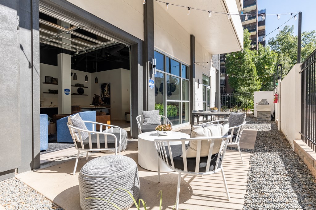 a patio with white chairs and tables and a building with glass doors