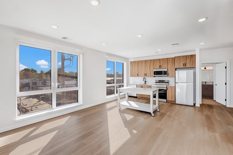 A modern kitchen with a dining table and chairs, a refrigerator, and a microwave.