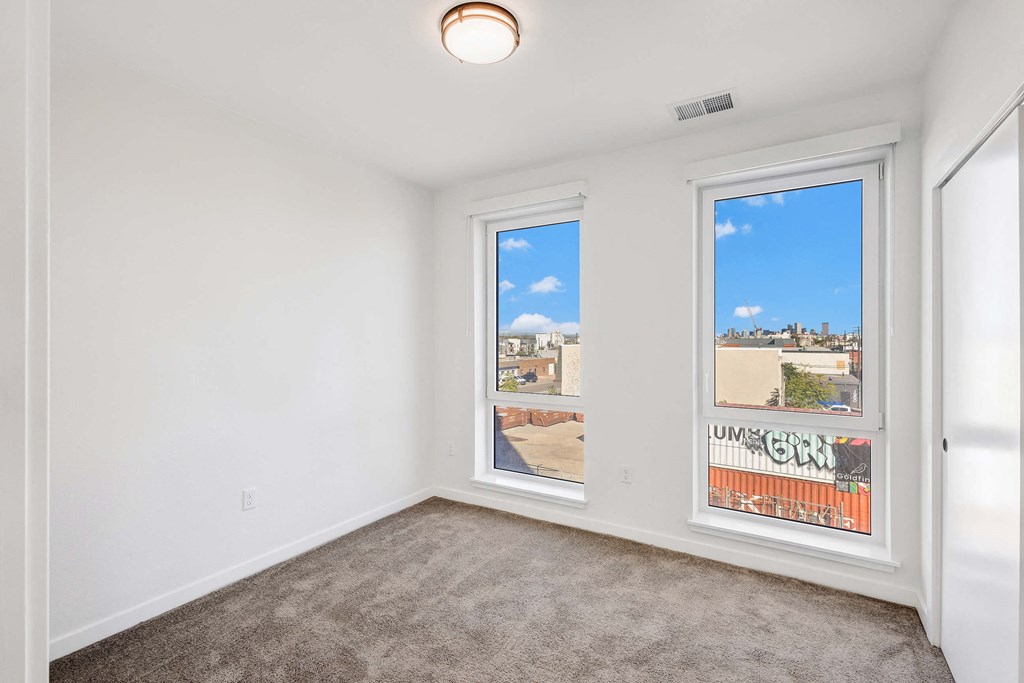 A room with two windows showing a view of a cityscape.