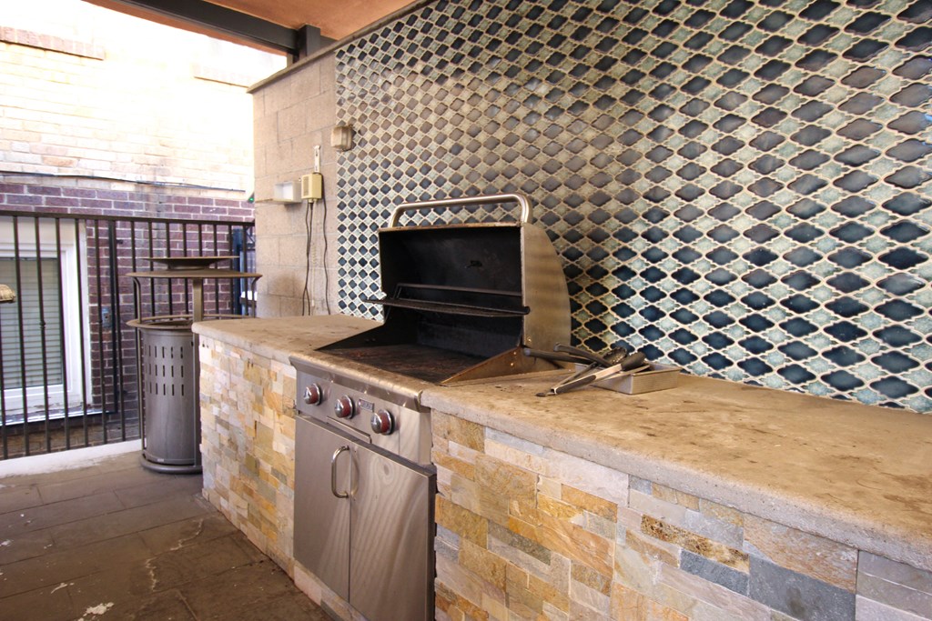 A tiled wall with a black oven on a stone counter.