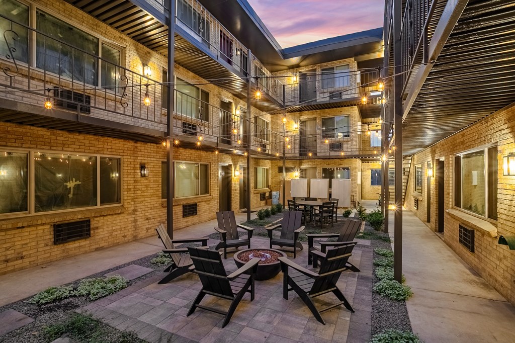 A patio with chairs and a table is surrounded by brick buildings.