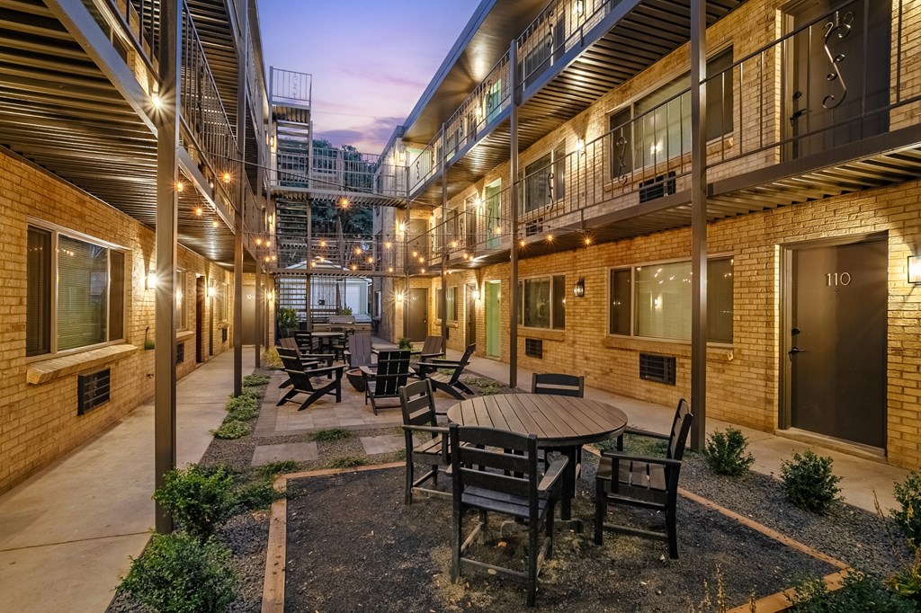 A patio with a table and chairs is surrounded by brick buildings.