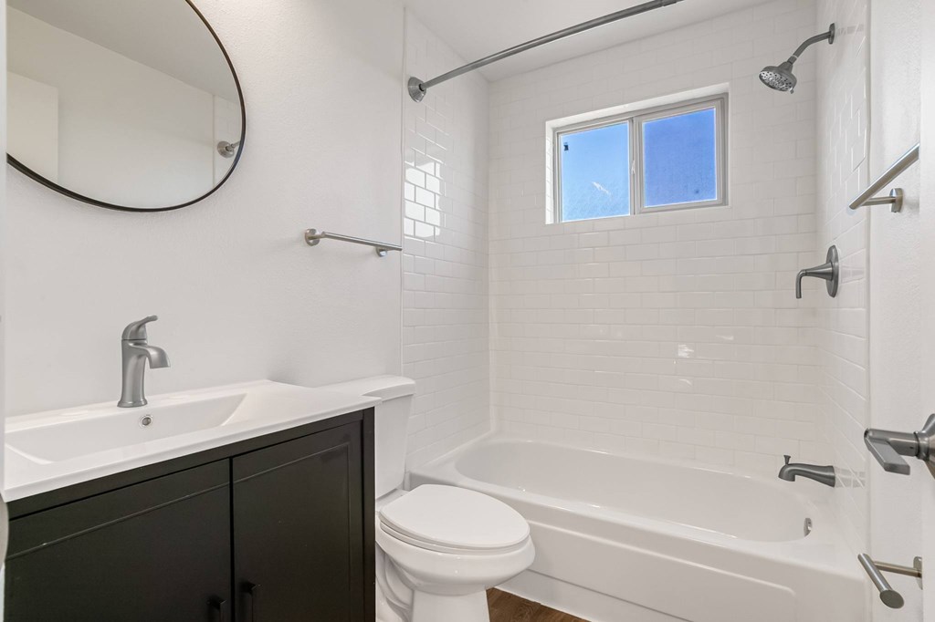 A white bathroom with a black cabinet and a window.