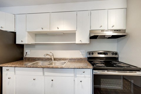 a kitchen with white cabinets and a stove and a sink