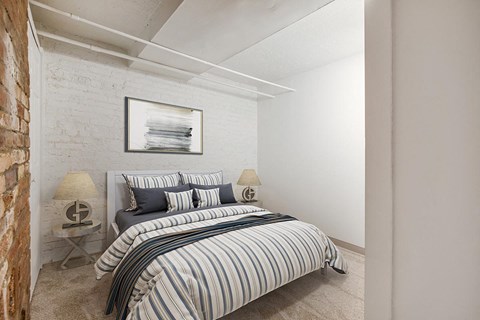 a bedroom with a bed and a white brick wall