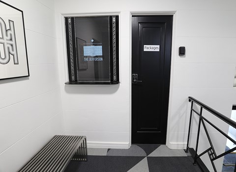 A black door with a sign that says "packages" is next to a window.