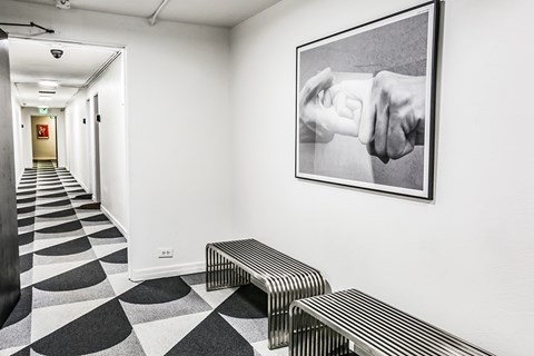A hallway with a bench and a picture of two hands on the wall.