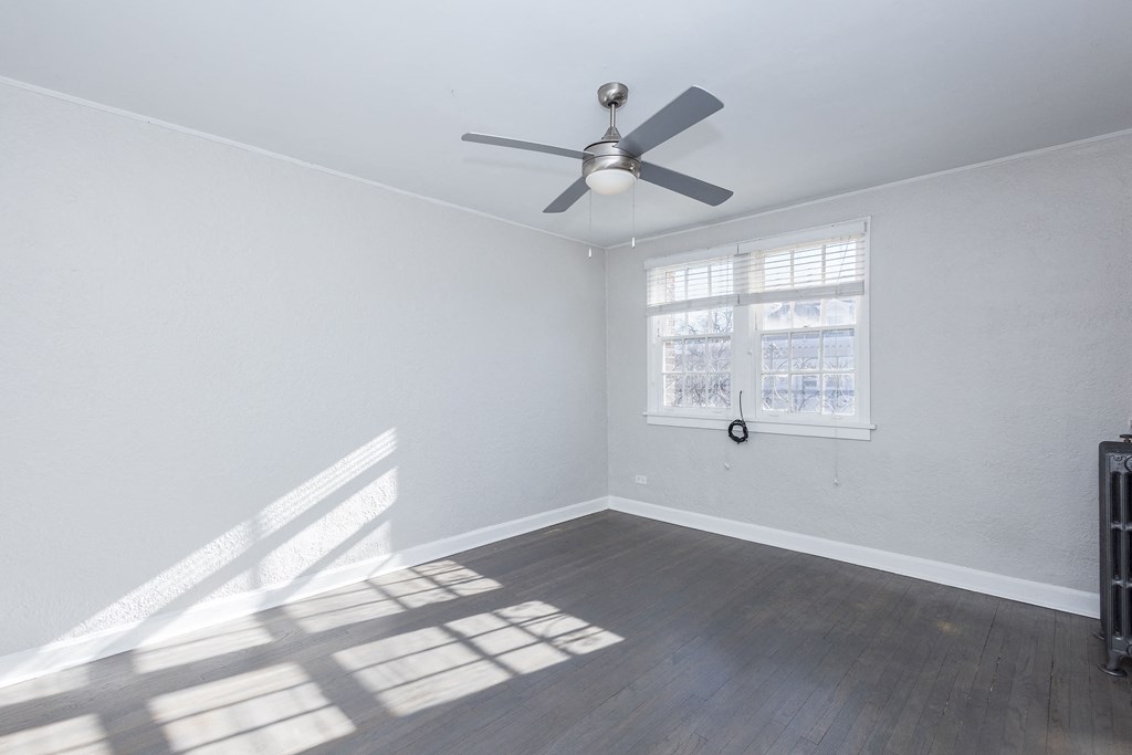 A room with a ceiling fan and a window letting in sunlight.