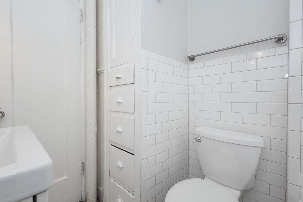 A white toilet in a bathroom with white tiles.