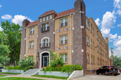 A large brick building with a black car parked in front.