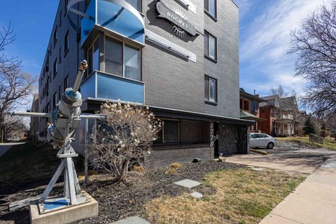 A modern building with a blue and grey facade and a sculpture in front.