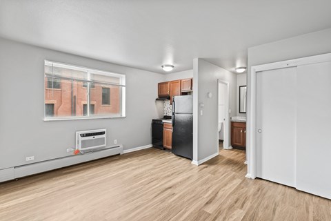 A kitchen with a black fridge and wooden floors.