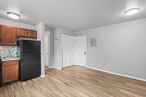 A kitchen with a black fridge and wooden cabinets.