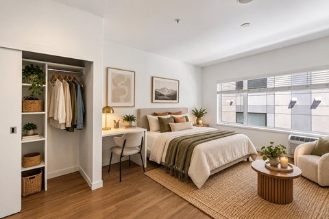 A bedroom with a bed, chair, and window.