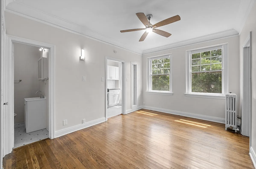 an empty living room with a ceiling fan and wood floors