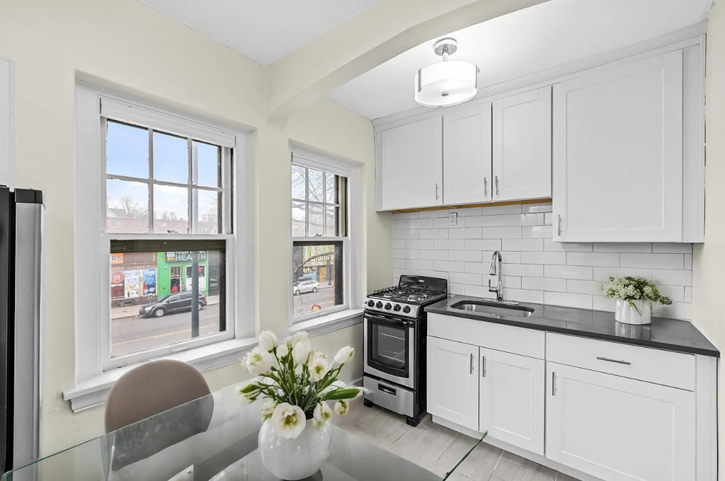 a white kitchen with a table and a window