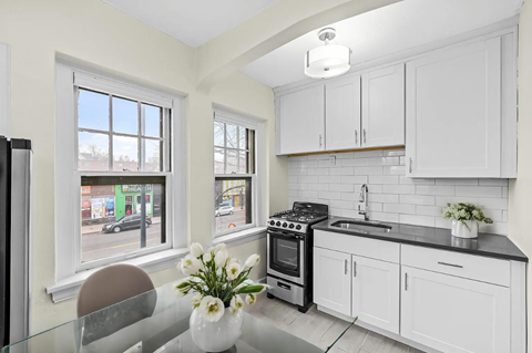 a white kitchen with a table and a window